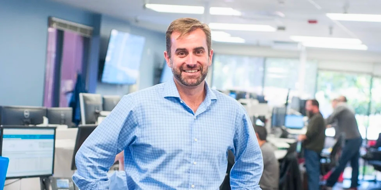 Chief Information Officer Jon Russell in a blue shirt standing confidently in an office environment