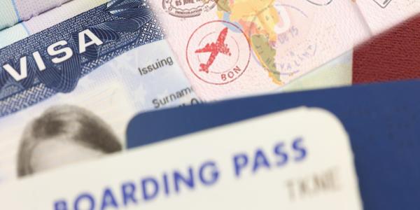 A close-up image of travel documents, including a visa, passport stamps, and a boarding pass, representing international travel processes.