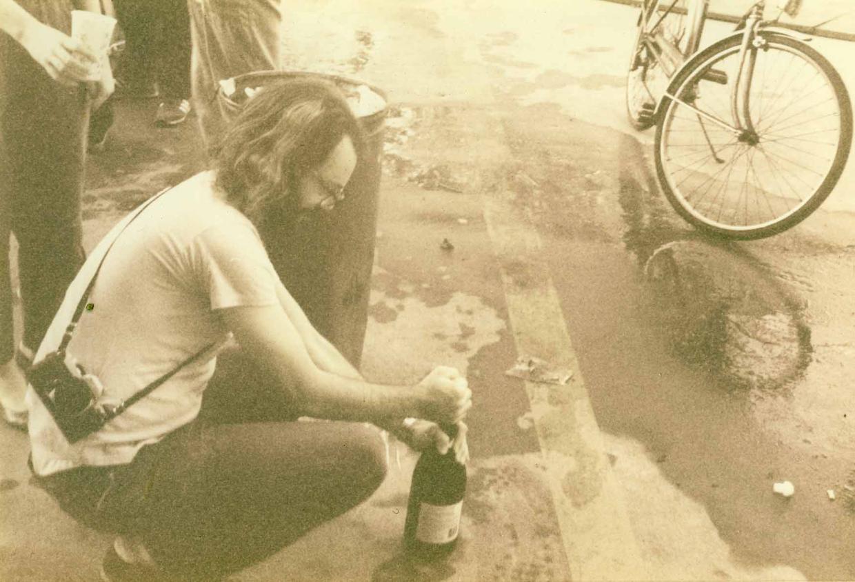 john bartelt crouching down to open bottle of champagne