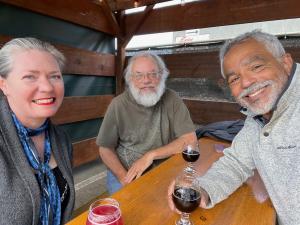 3 people sittng at a table sipping beer