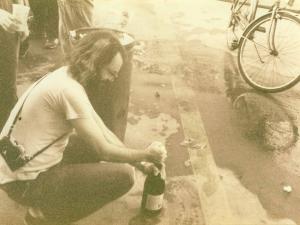 john bartelt crouching down to open bottle of champagne
